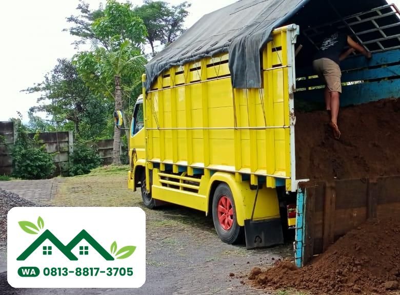 Truk kuning berisi tanah subur di halaman berumput