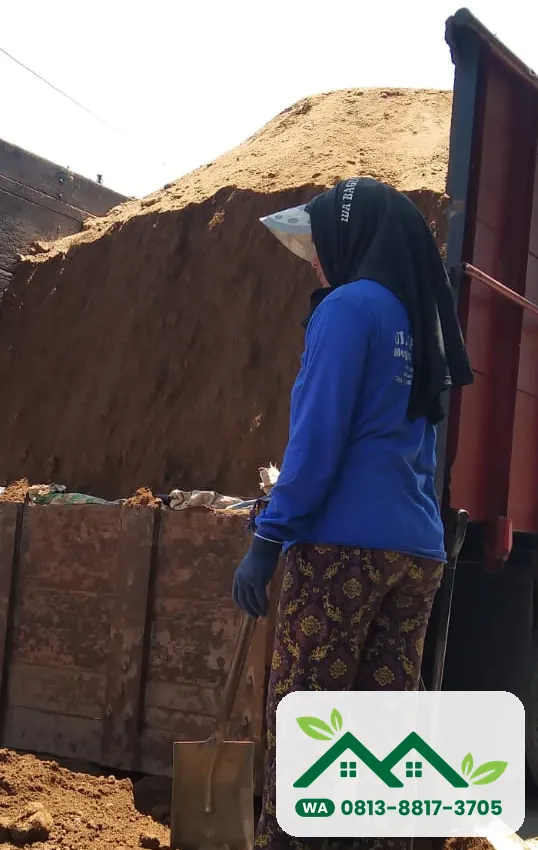 Pekerja membongkar tanah subur dari bak truk