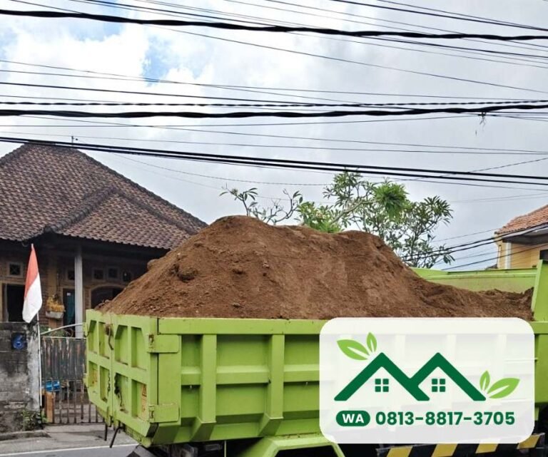 Dam truk hijau penuh tanah subur di jalan perumahan